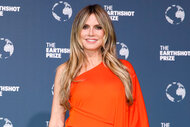 Heidi Klum smiles and wears a red dress on the red carpet