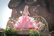 Glinda holds her wand up in a puffy pink dress in Wicked