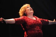 Susan Boyle performs onstage in a red dress.