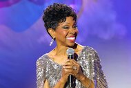 Gladys Knight performs onstage in a silver dress.