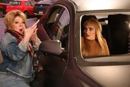 Melissa McCarthy standing outside of a car and Chloe Fineman sitting in the passenger seat.