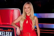 Kelsea Ballerini smiling and posing next to her coach chair on The Voice Season 27, Episode 1.