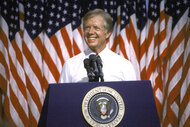 President Jimmy Carter stands at the podium in front of American flags