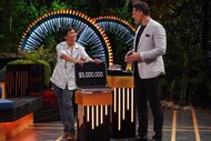 Joe Manganiello watches Dickson Wong stand with their open briefcase on Deal or No Deal Island Episode 204.