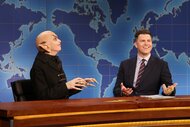 Sarah Sherman bald with pointy ears next to Colin Jost in a suit.