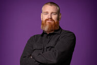 Wes Bergmann wears a black shirt in front of a purple background for House Of Villains Season 2.