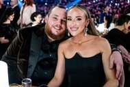 Luke Combs and wife Nicole Hocking smiling at the 66th Grammy Awards.