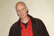 Matt Frewer wears a red shirt and smiles at the Grand Slam/Sci-Fi Summit XV