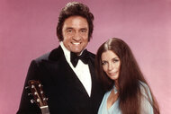 Johnny Cash and June Carter Cash pose together with a guitar