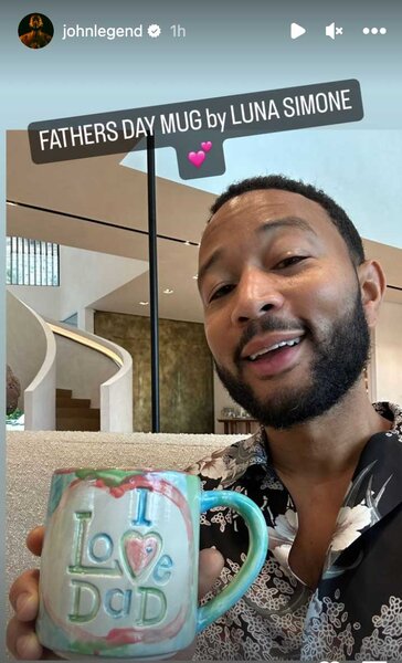 John Legend holding a mug that says I Love Dad.