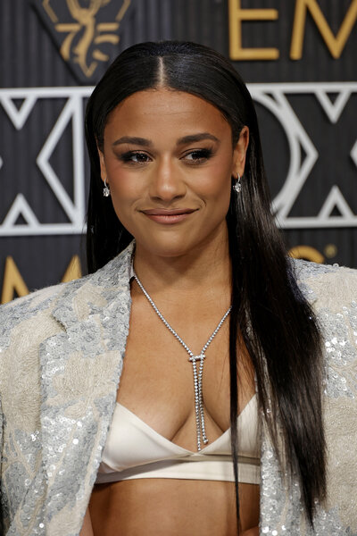 Ariana DeBose smiles in a silver bralette and blazer.