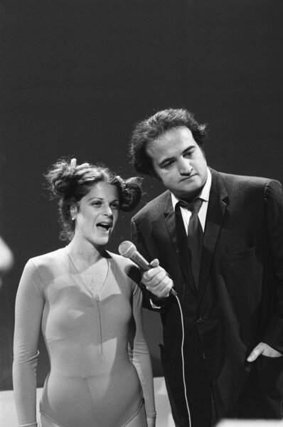 Gilda Radner speaks into a mic John Belushi holds on Saturday Night Live Season 1 Episode 23.