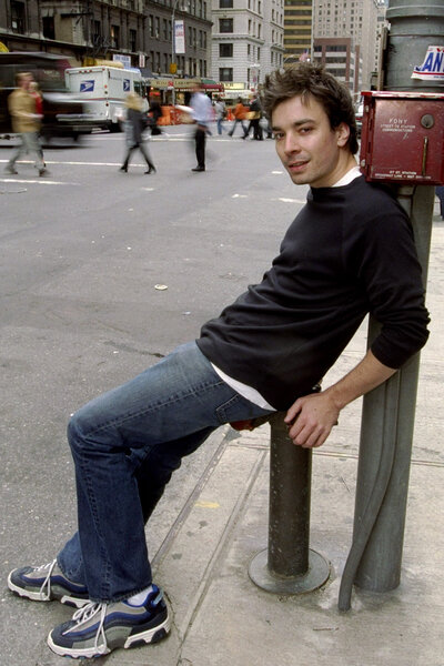 Jimmy Fallon leans against a sign on a new york city street