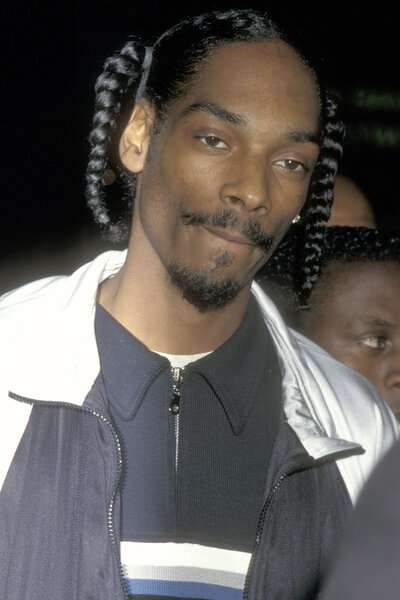 Snoop Dogg wears a track jacket with his hair in pigtail braids