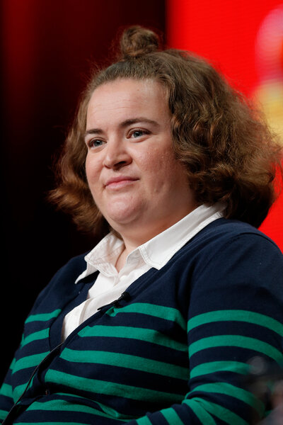 Betsy Sodaro wears a striped shirt on stage