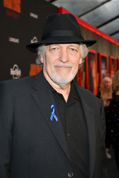 Clancy Brown smiling in front of a step and repeat.