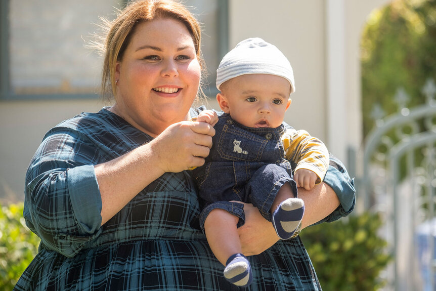 Kate holding their baby and waving his hand