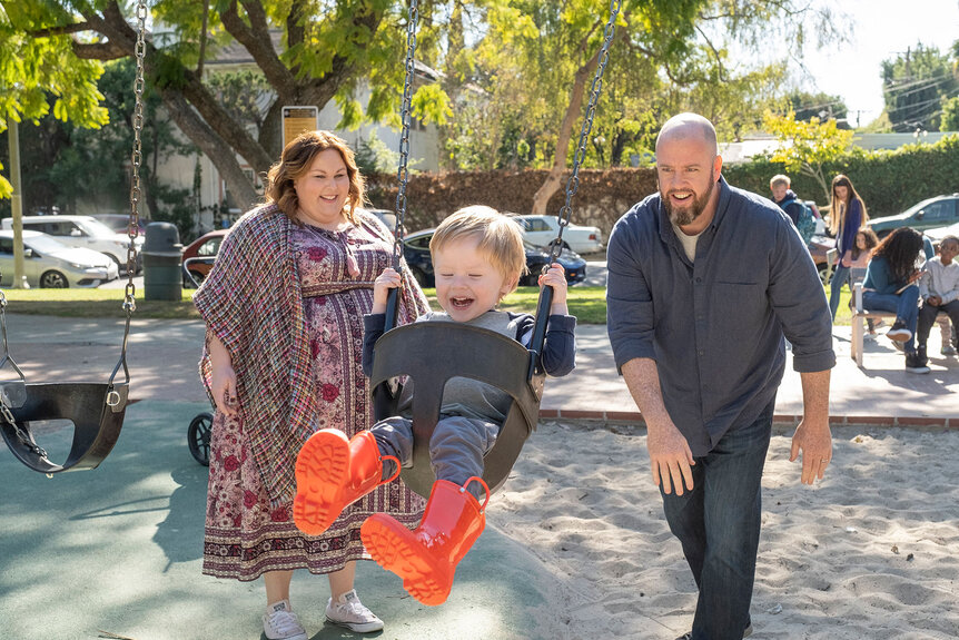 Kate and Toby pushing baby Jack on a swing at the playground