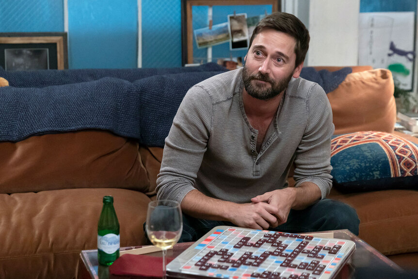 Max sitting on his couch with a scrabble board in front of him