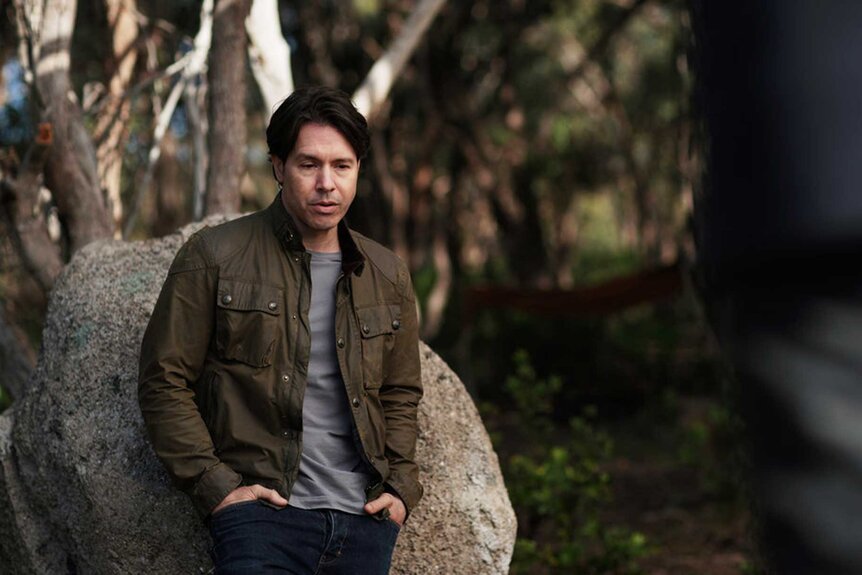 Jon Seda as Dr. Sam leaning against a rock on set of La Brea.