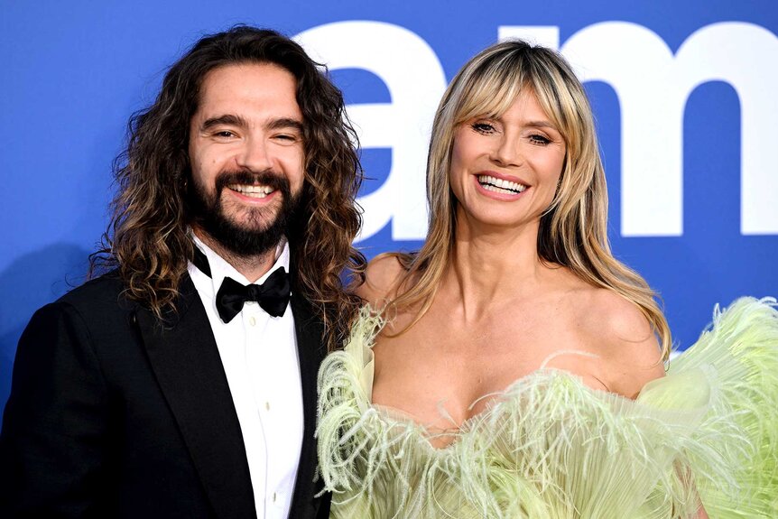 Tom Kaulitz posing next to Heidi Klum at an event.