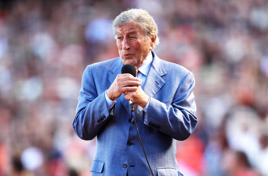 Tony Bennett singing in front of a crowd of people.