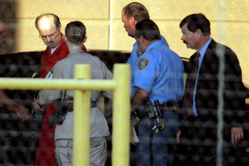 Dennis L. Rader being escorted by officers into the El Dorado Correctional Facility.