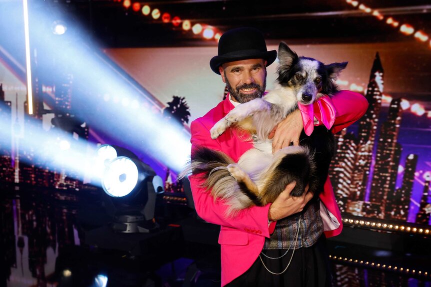 Adrian Stoica holding his dog Hurricane closely while posing for the camera.