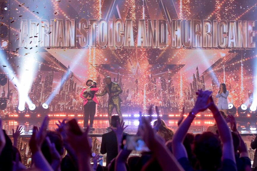 Audience members celebrating as Adrian Stoica and Hurricane celebrate with Terry Crews on stage.