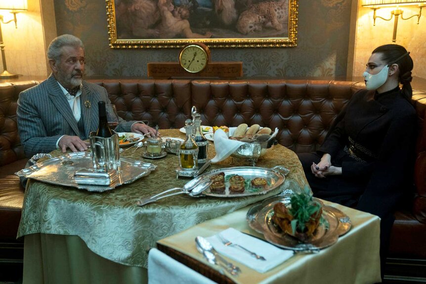 Cormac and Adjudicator speaking over a meal during a scene from The Continental.