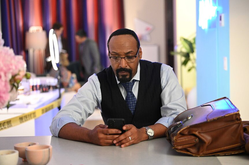 Alec Mercer sitting at a table and looking down with his hands folded.