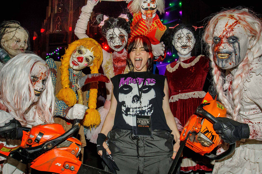 Billie Eilish poses with costumed characters from Halloween Horror Nights