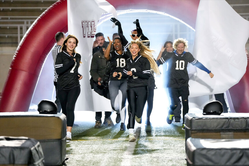 Anfisa Arkhipchenko, Jax Taylor, OMAROSA, Corinne Olympios, Bobby Lytes, Tiffany “New York” Pollard, and Jonny Fairplay run onto a football field while wearing foot ball jerseys