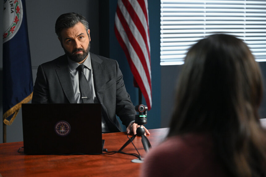 Jace Richards sitting at a desk talking to another character.