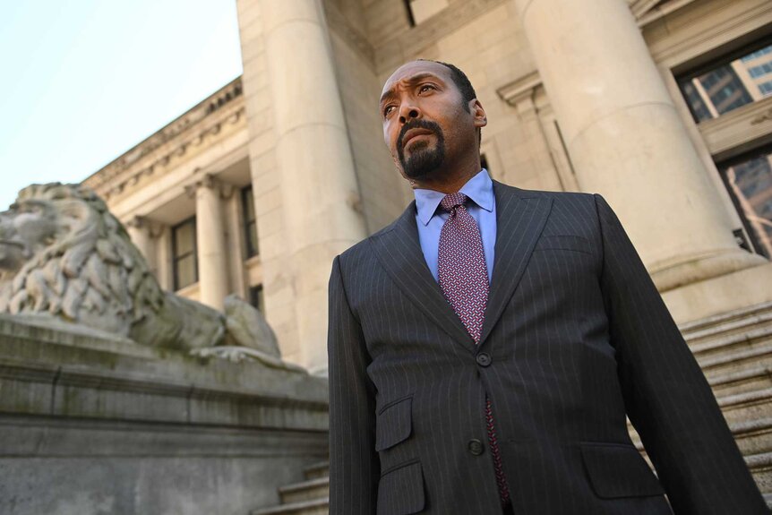 Alec Mercer, wearing a blue blazer, looking into the distance.