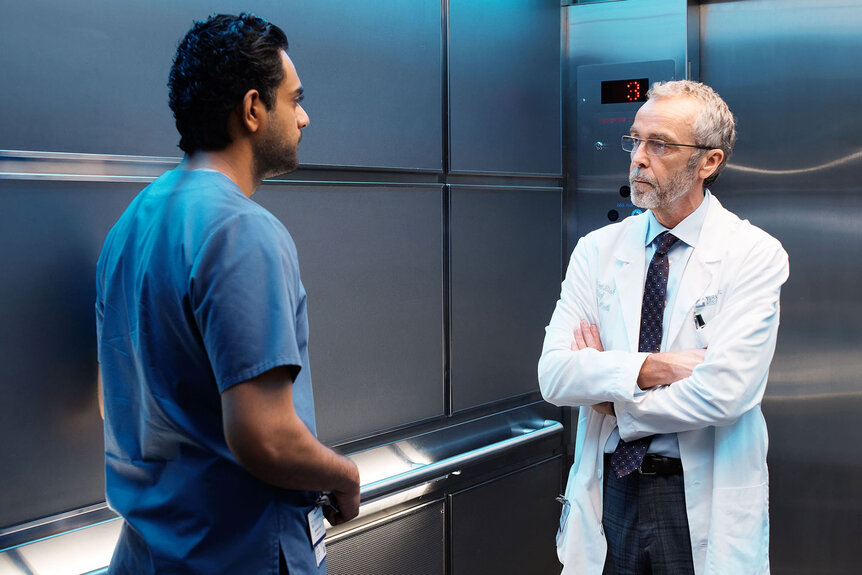 Dr. Bashir “Bash” Hamed (Hamza Haq) and Dr. Jed Bishop (John Hannah) stand in an elevator together