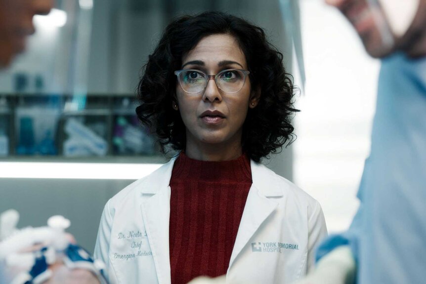 A close up of Dr. Neeta Devi in the middle of two hospital workers having a conversation.