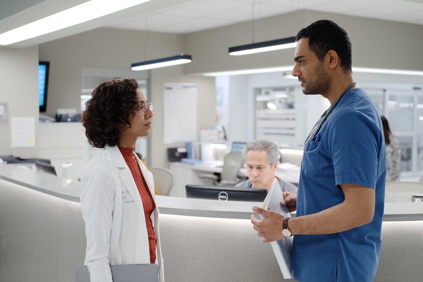 Dr. Neeta Devi and Dr. Bashir Hamed having a conversation together in the hospital by the front desk.