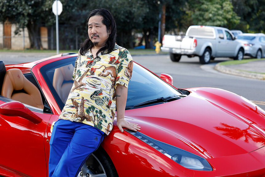 Bobby Lee leans on Magnum's red corvette