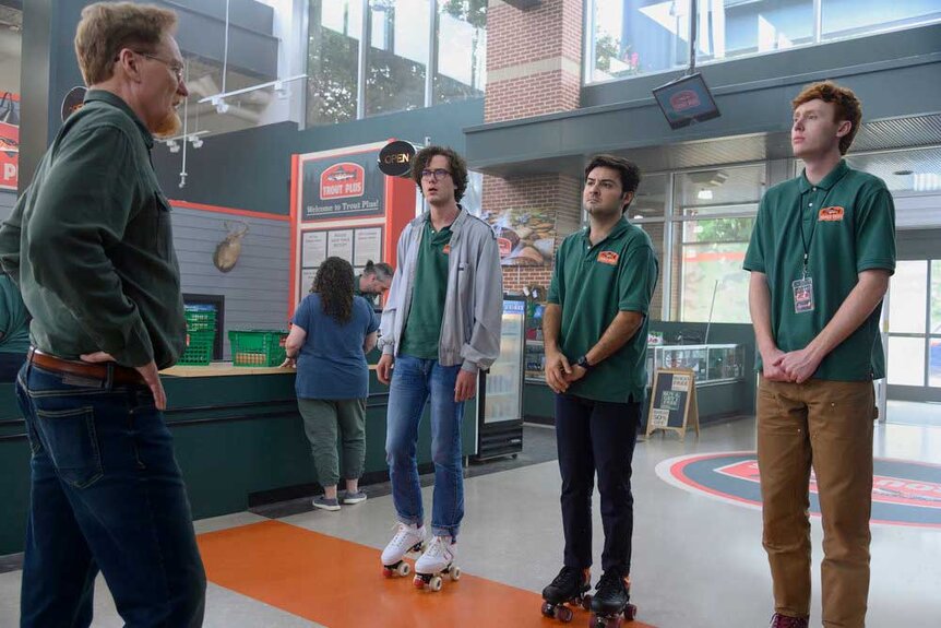 Martin, John, and Ben standing in front of Farley while having a conversation.