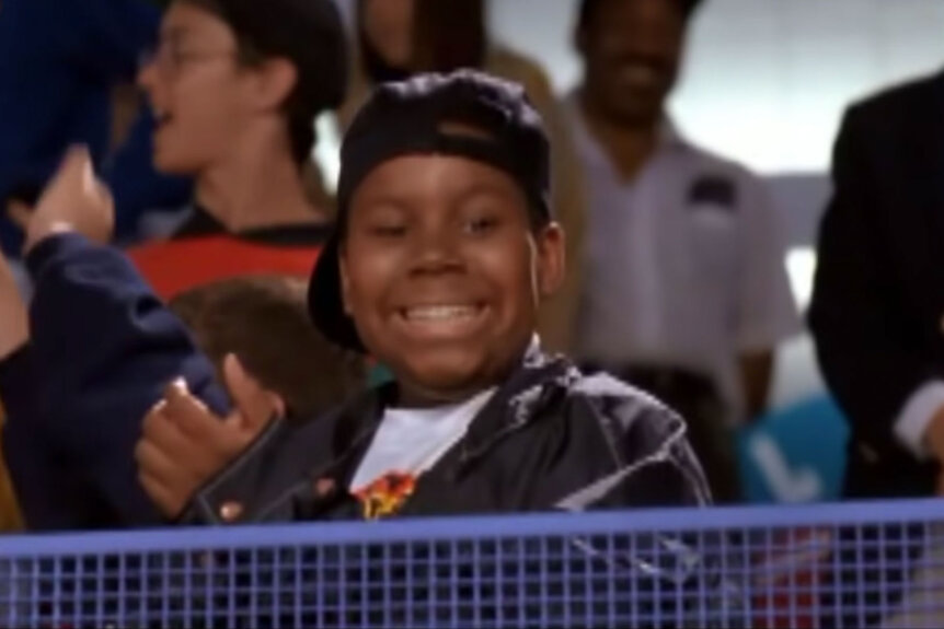 Kenan Thompson claps from the stands during a hockey game