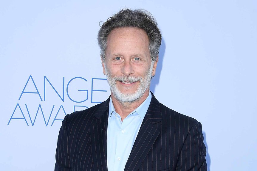 Steven Weber smiles in a suit.