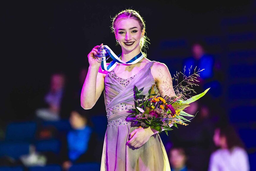 Amber Glenn holds her bronze medal and bouquet.