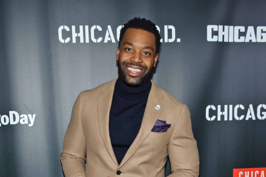 LaRoyce Hawkins smiles in a beige suit.