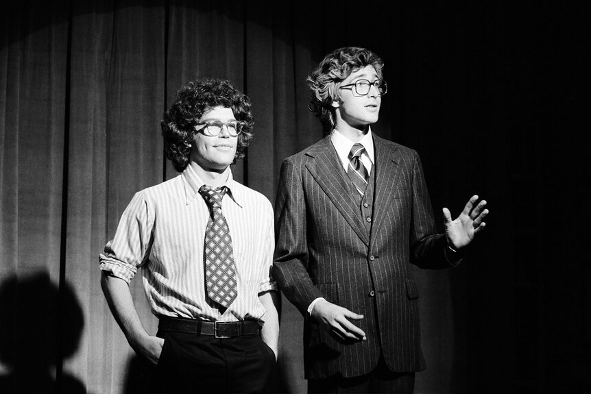 Al Franken and Tom Davis stand onstage during a skit