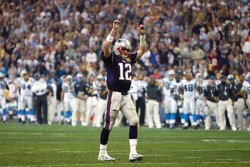 Tom Brady #12 of the New England Patriots raises his arms in celebration of a play against the Carolina Panthers during Super Bowl XXXVIII