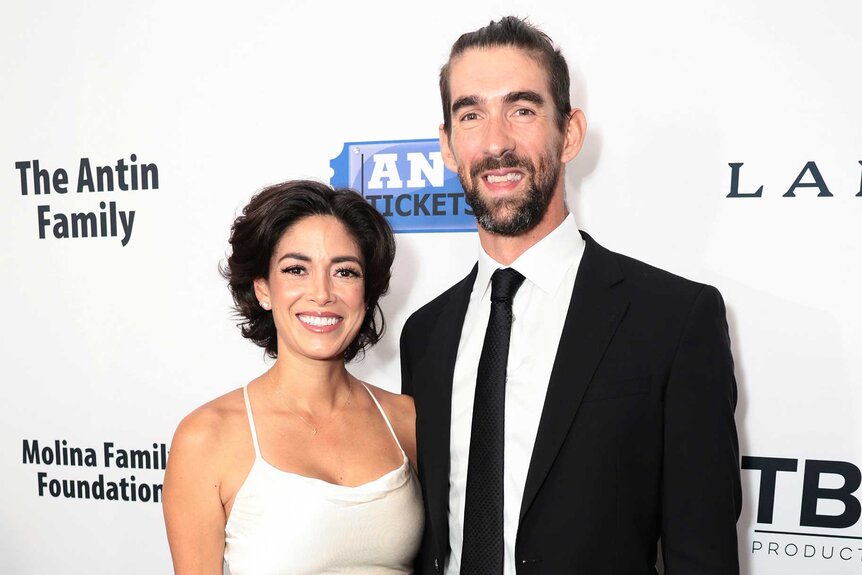 Michael and his wife Nicole Phelps wears a white dress and smiles together