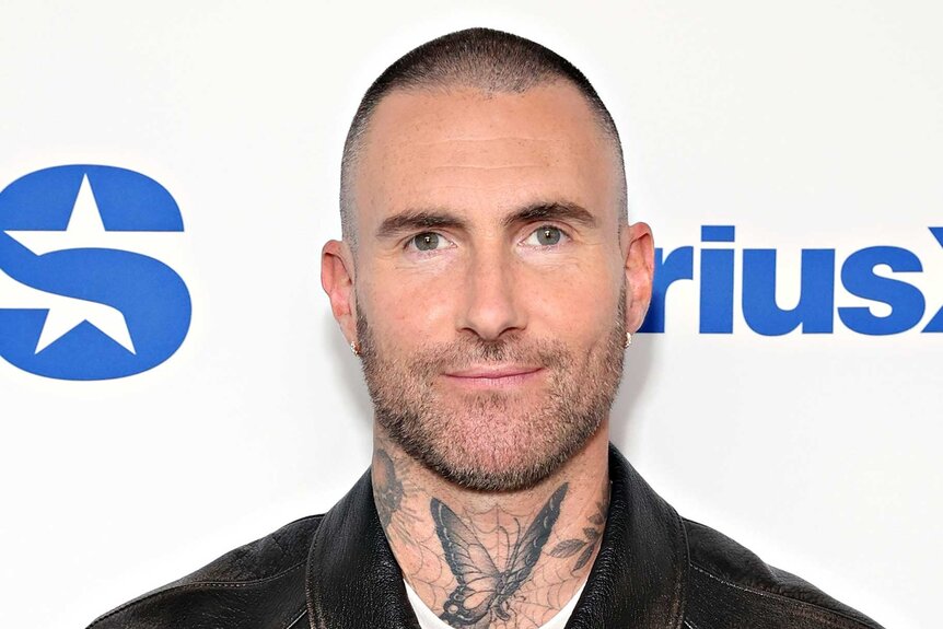 Adam Levine smiles in a leather jacket