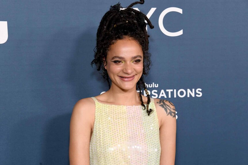 Sasha Lane smiles in a pastel dress.