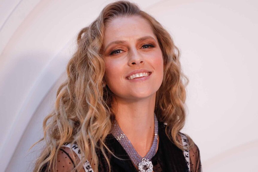 Teresa Palmer smiles in a black dress.